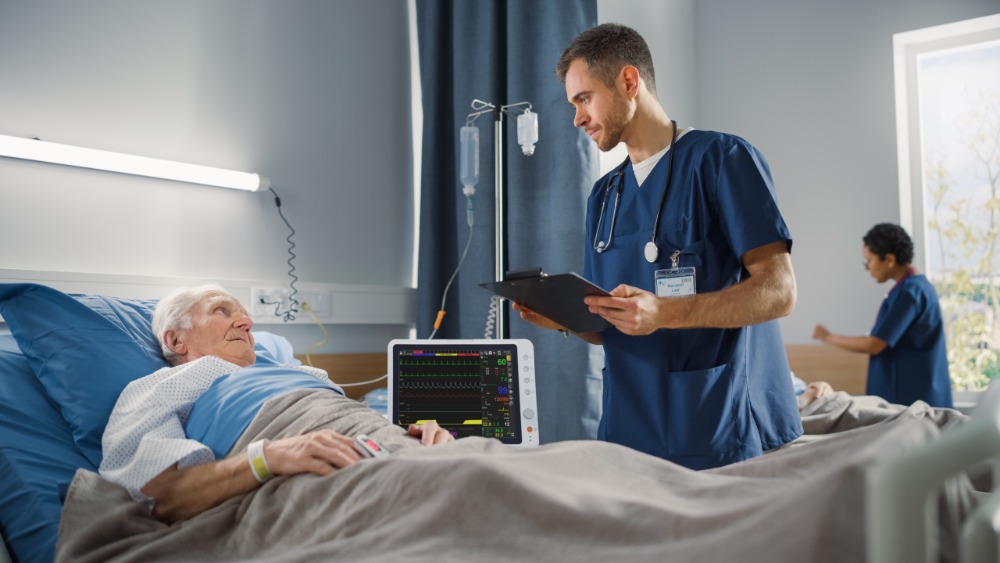 bm7-patient-monitor-in-clinical-use-at-bedside BM7 patient monitor in clinical use at hospital bedside with healthcare professional and elderly patient