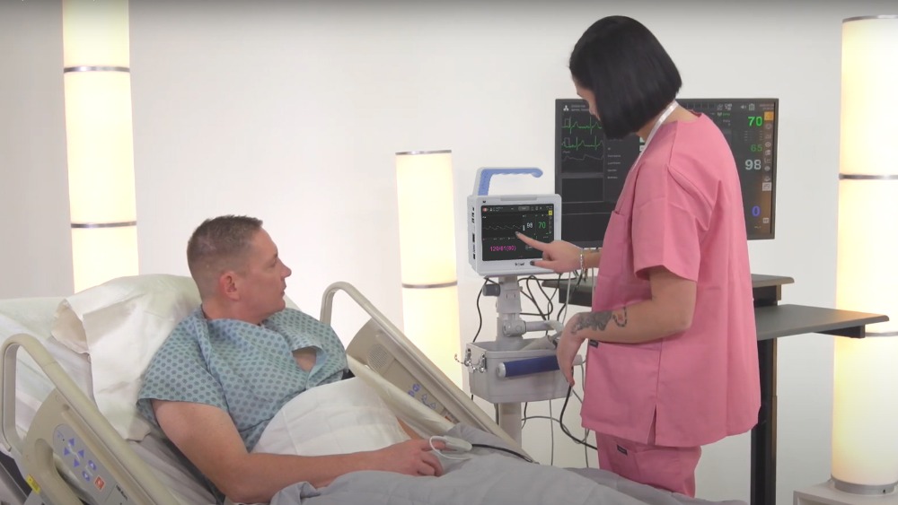 bm1-vital-signs-monitor-in-clinical-use-at-bedside BM1 compact vital signs monitor in clinical use at bedside with healthcare professional performing spot-check and triage