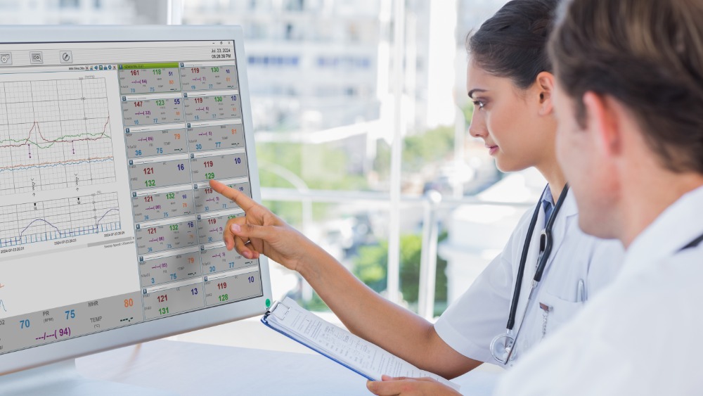 fc-central-clinical-setting-doctors-reviewing-multi-patient-fetal-monitoring-screen Two healthcare professionals reviewing FC Central multi-patient fetal monitoring software showing 16-channel patient data with fetal heart rate measurements and uterine contraction monitoring in clinical setting
