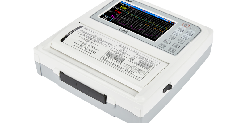 fc1400-fetal-monitor-right-front-angle-view FC1400 fetal monitor right-front angle view with color touch screen displaying fetal heart rate waveforms and printer cover with quick guide overlay