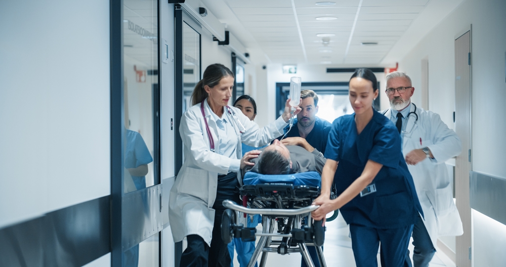 Healthcare professionals performing emergency patient transport with portable monitoring devices connected to a centralized hospital monitoring network